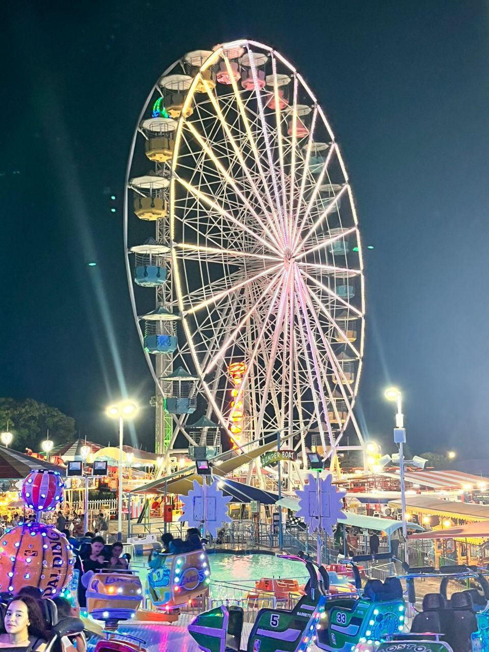 A roda-gigante do parque iluminada à noite, com luzes douradas nos raios